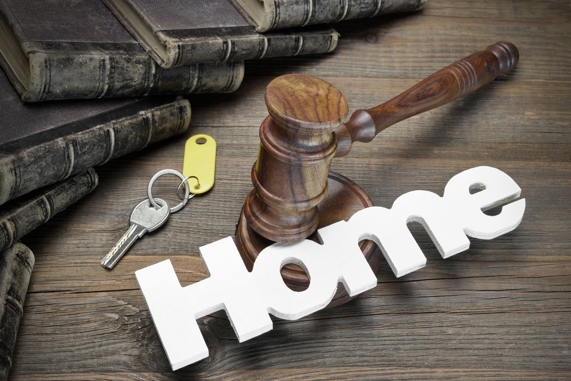 Gavel, house key, and law book on table representing conveyancing process.