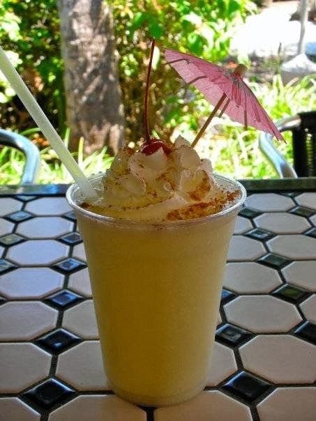A smoothie with whipped cream and a pink umbrella on top