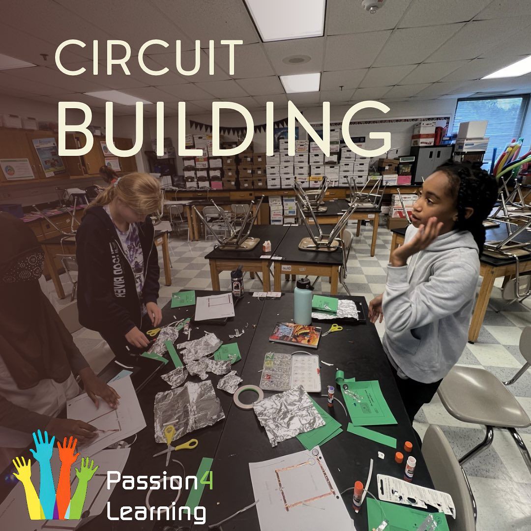 Students building circuits at a table, in a classroom. 