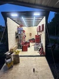 Open garage with tools, red equipment, and shelves inside at dusk