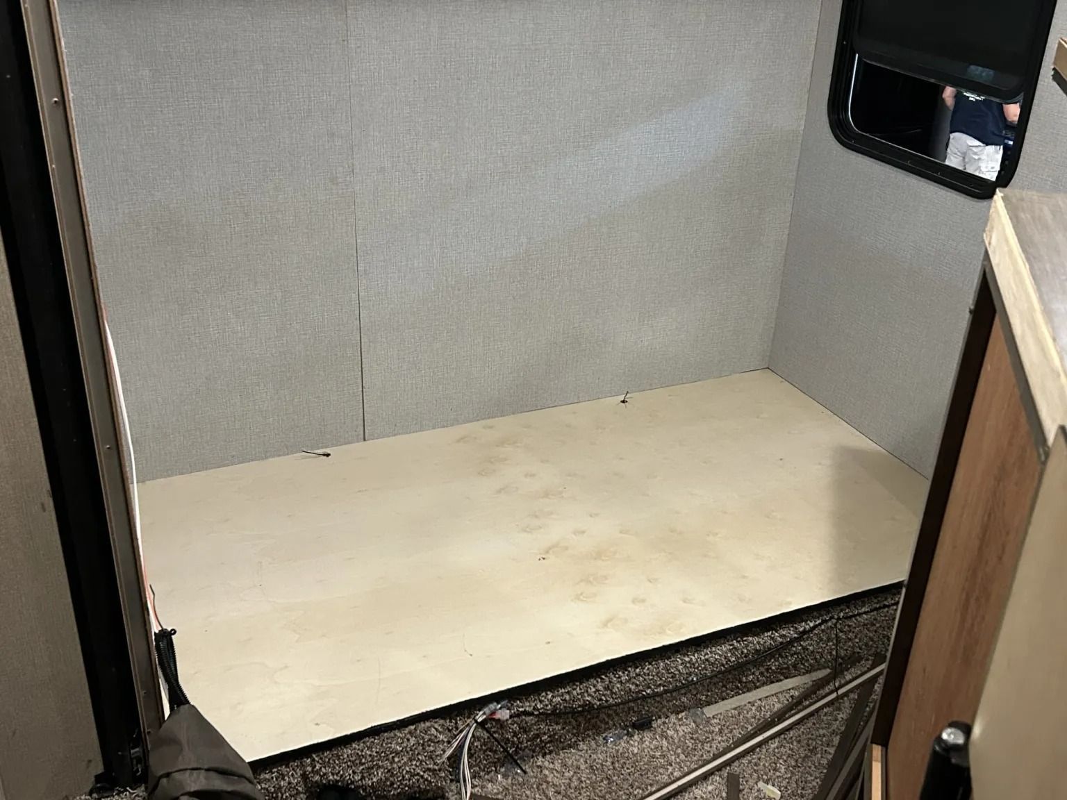Small empty beige compartment with a black-framed opening and a wooden panel on the right