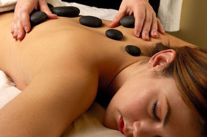 Eine Frau bekommt eine Massage mit heißen Steinen auf ihrem Rücken.