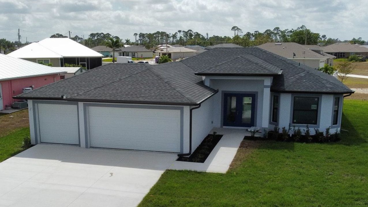 Light blue house with a dark gray roof, two-car garage, and green lawn.