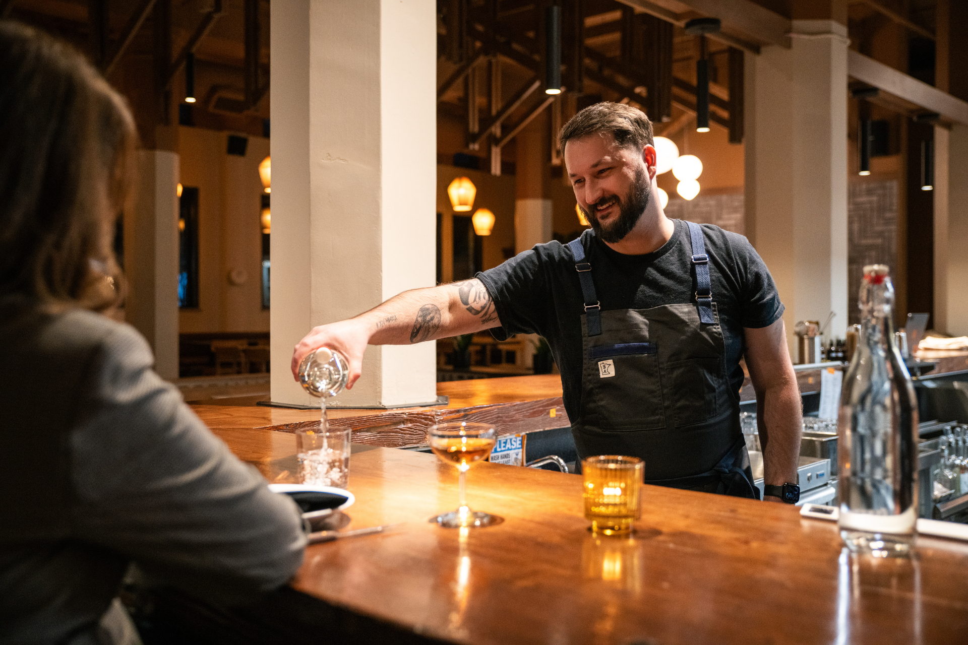 Man pouring drink at bar in Craftmade Apron.