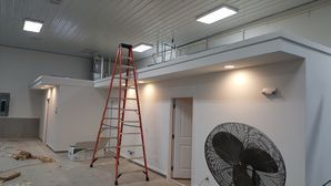A room with a ladder and a fan in it.
