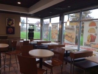 The inside of a fast food restaurant with tables and chairs