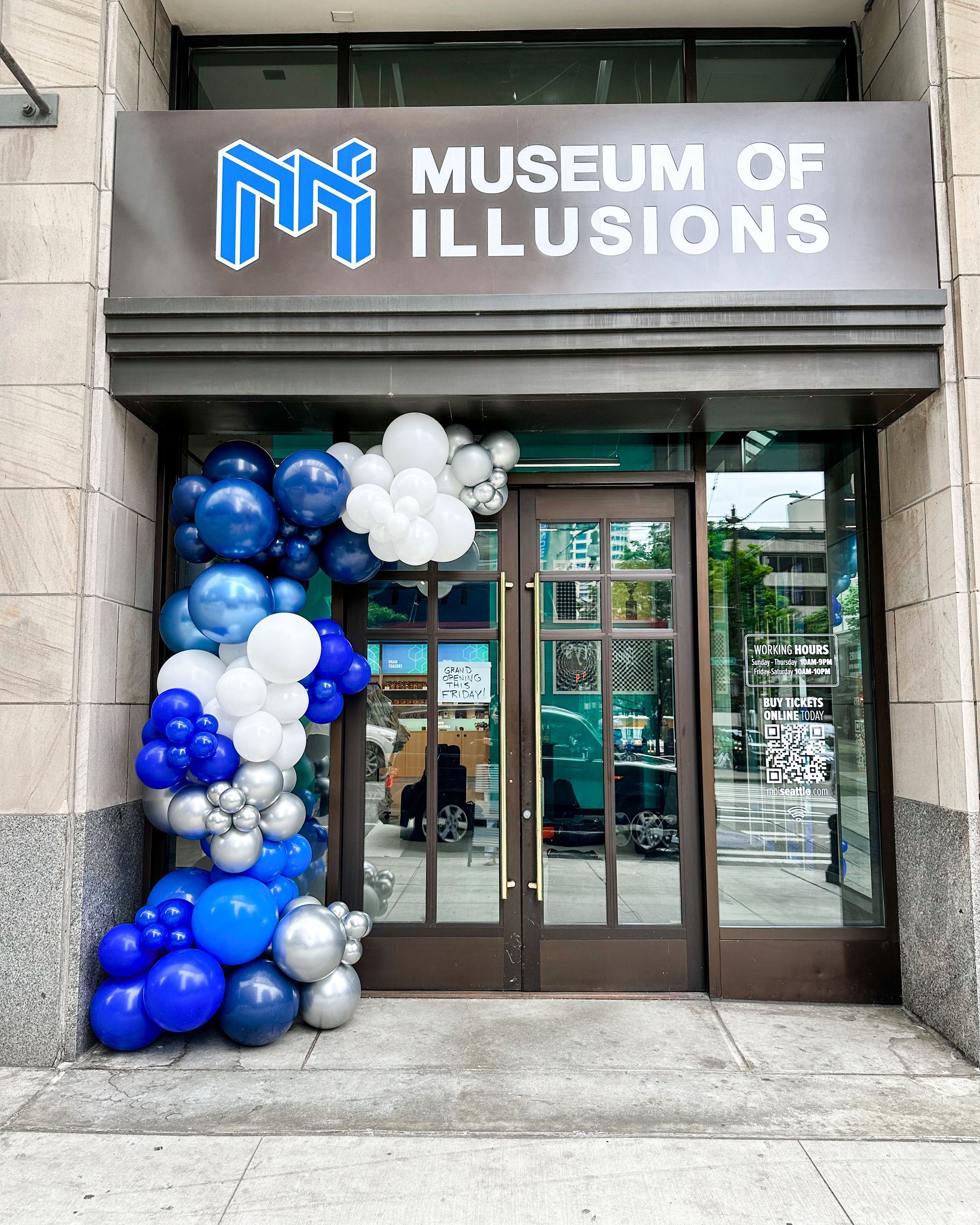 The entrance to the museum of illusions is decorated with blue and white balloons.