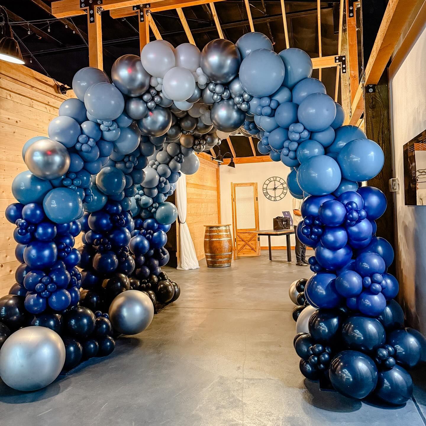 Balloon archway in shades of blue and silver, indoors.