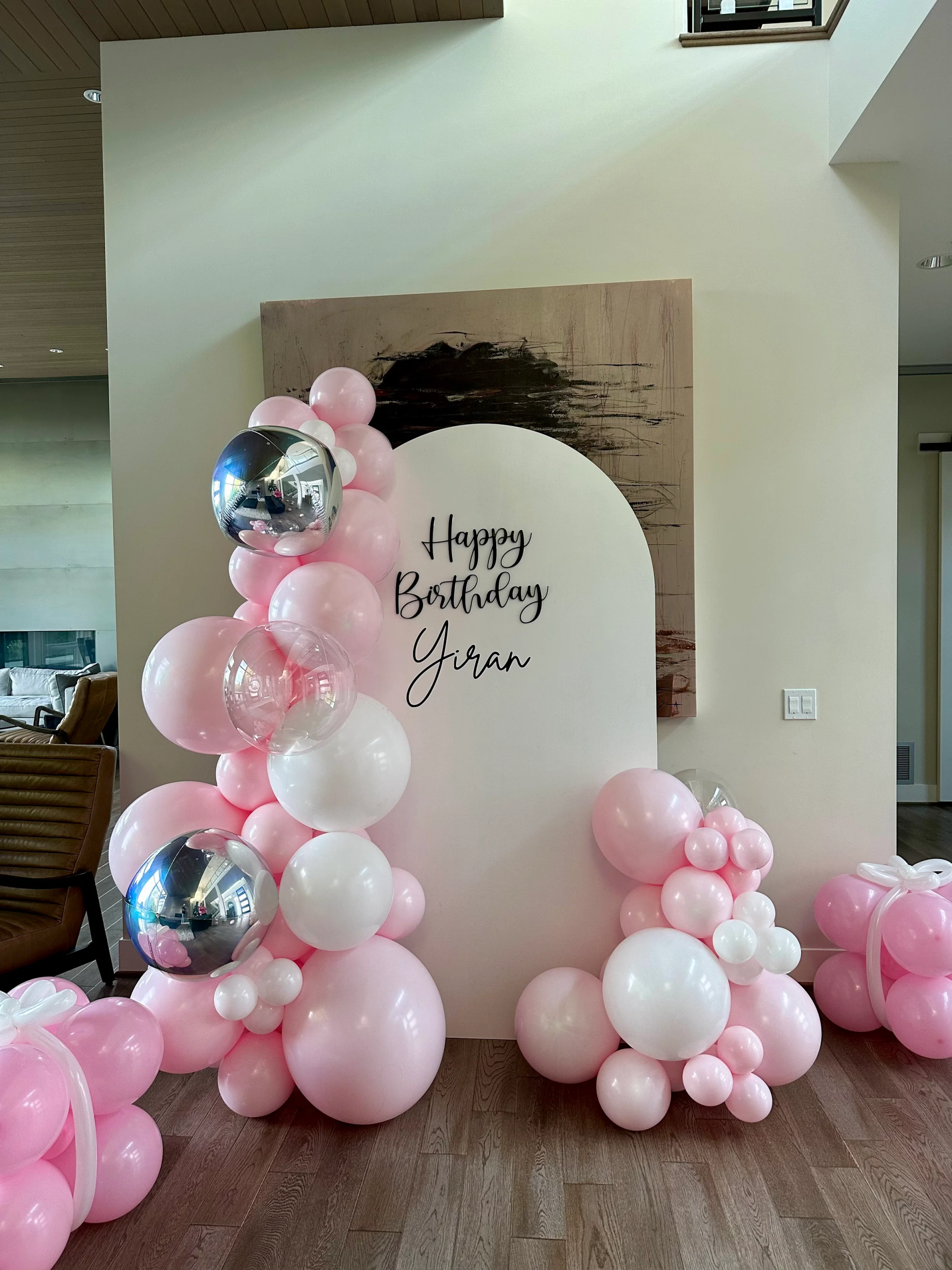 A room filled with pink and white balloons for a birthday party.