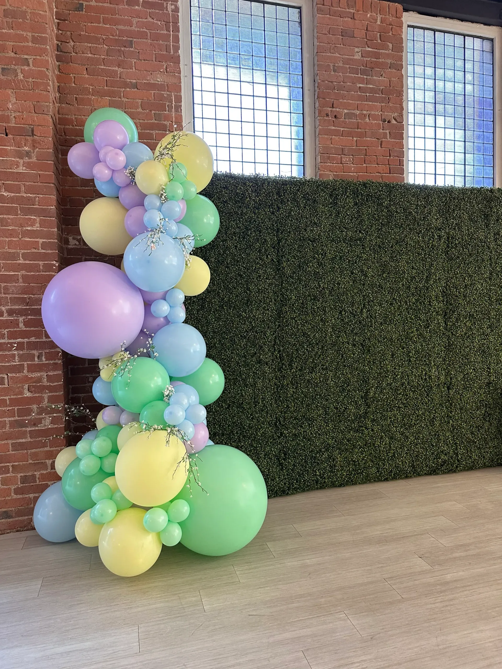 A bunch of balloons are sitting in front of a brick wall.