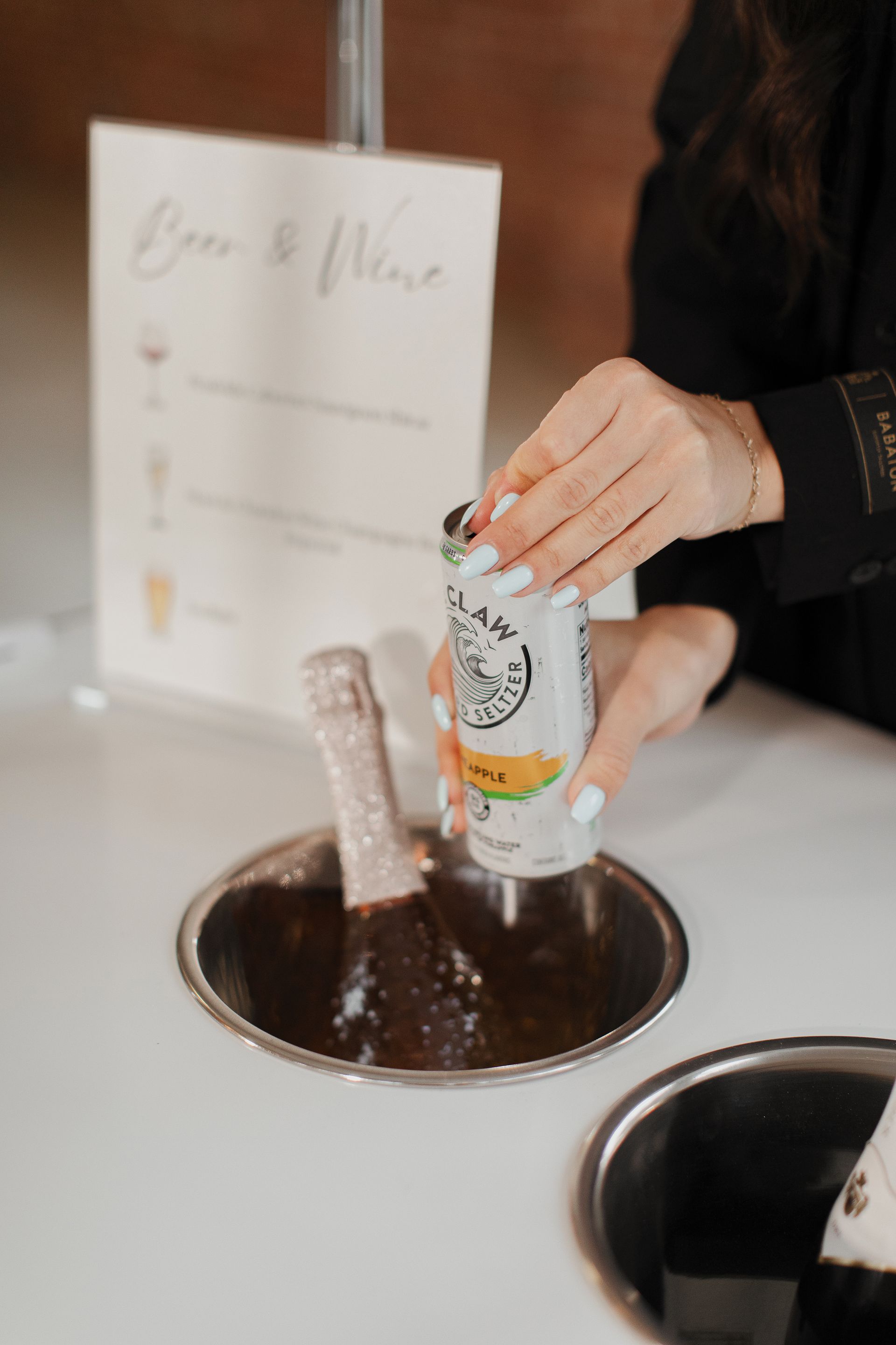 A woman is pouring a can of soda into a bottle of wine.