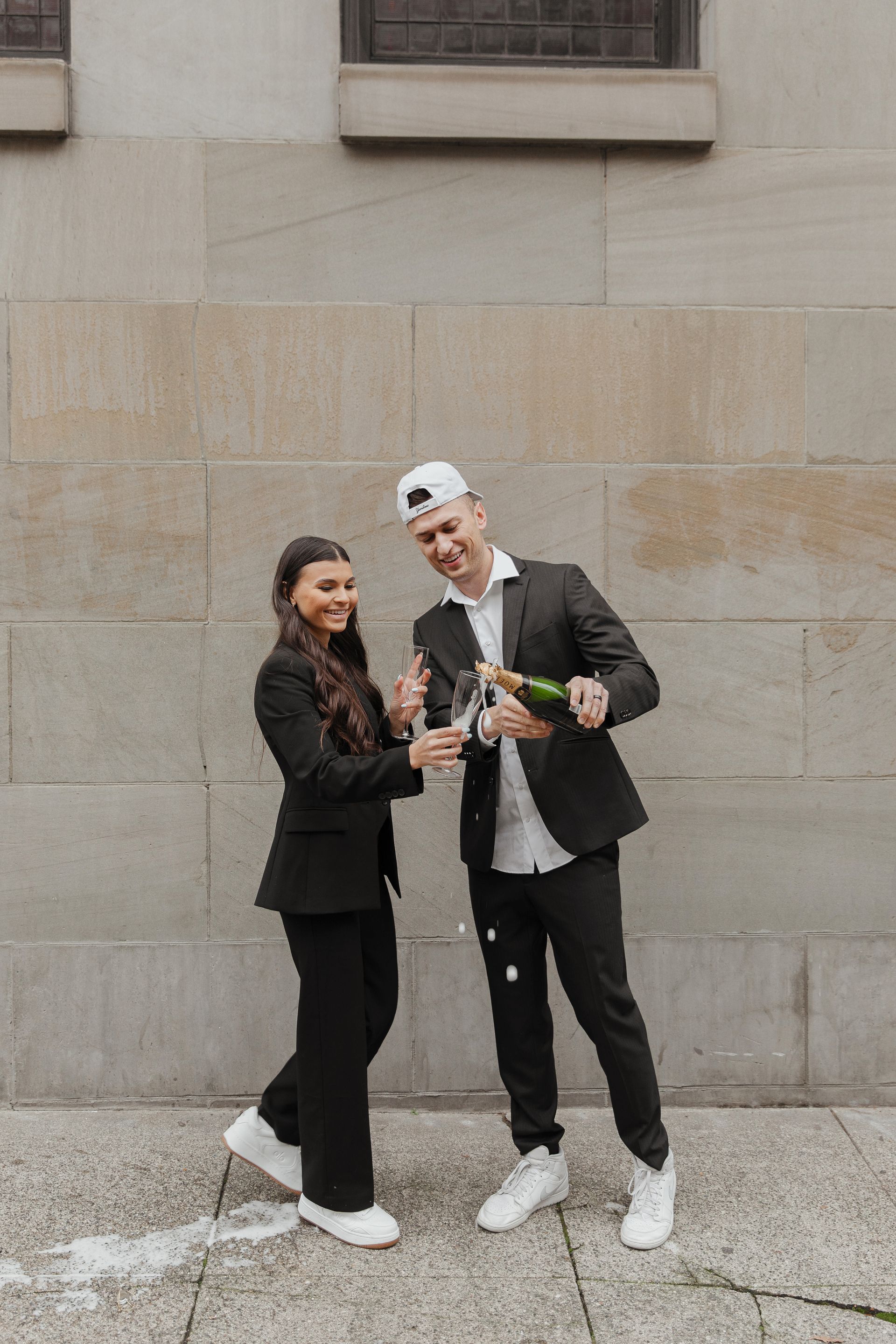 A man and a woman are standing next to each other holding bottles of champagne.