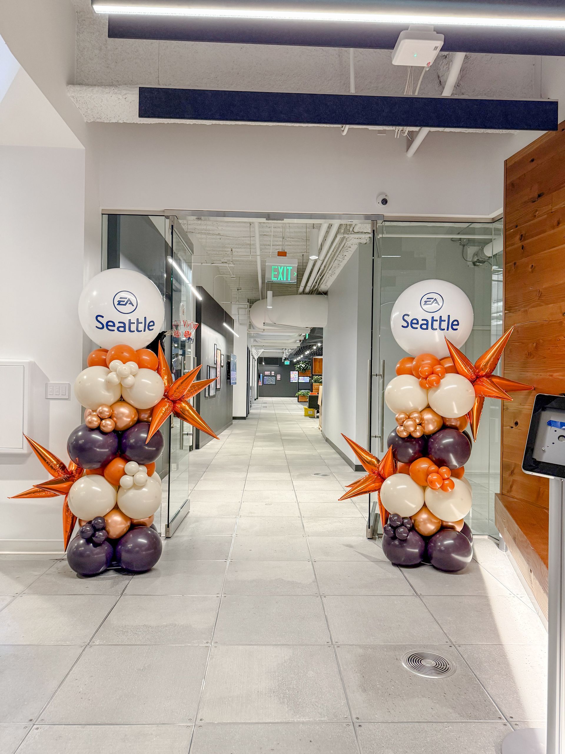 Two balloon columns with orange and white balloons frame an office doorway for EA Seattle.