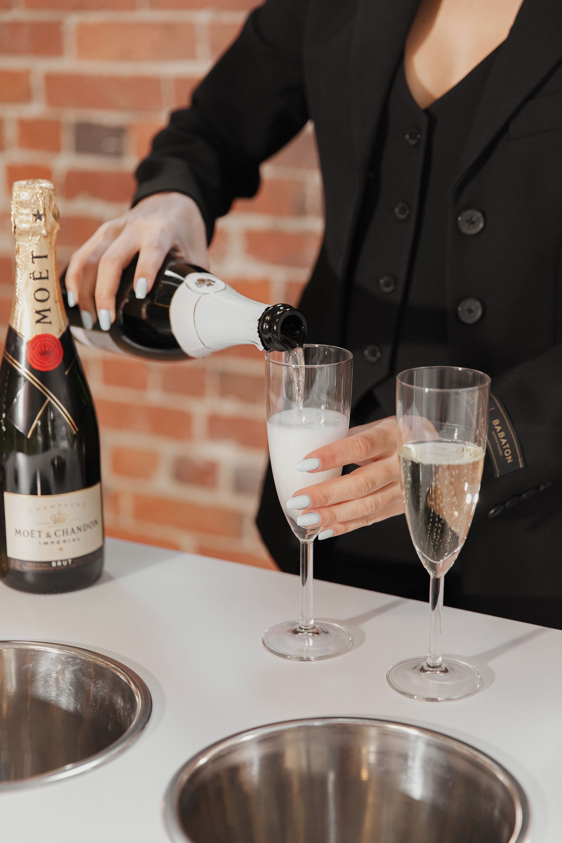 A woman is pouring champagne into a glass on a table.