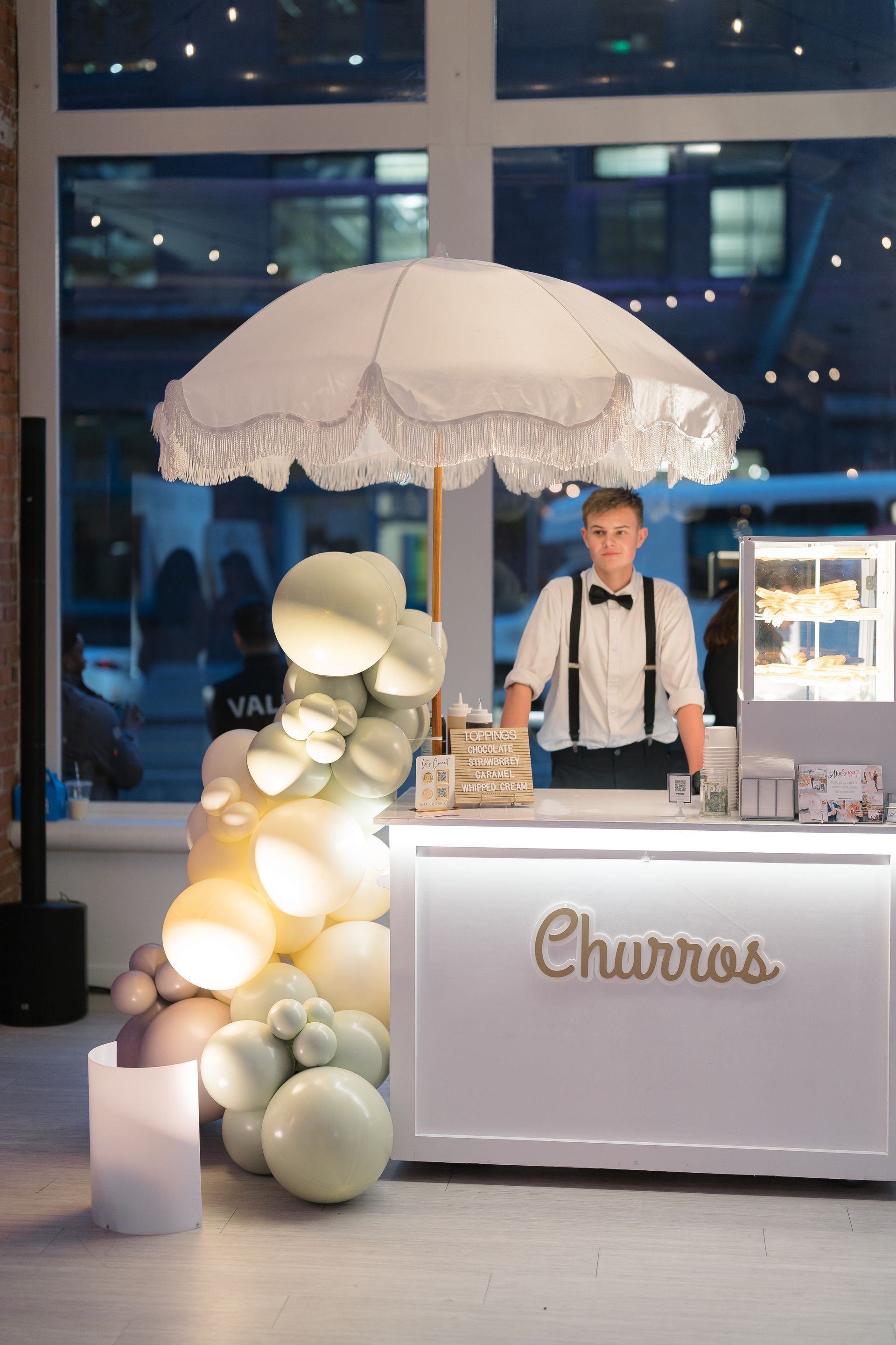 A man is standing in front of a churros stand.