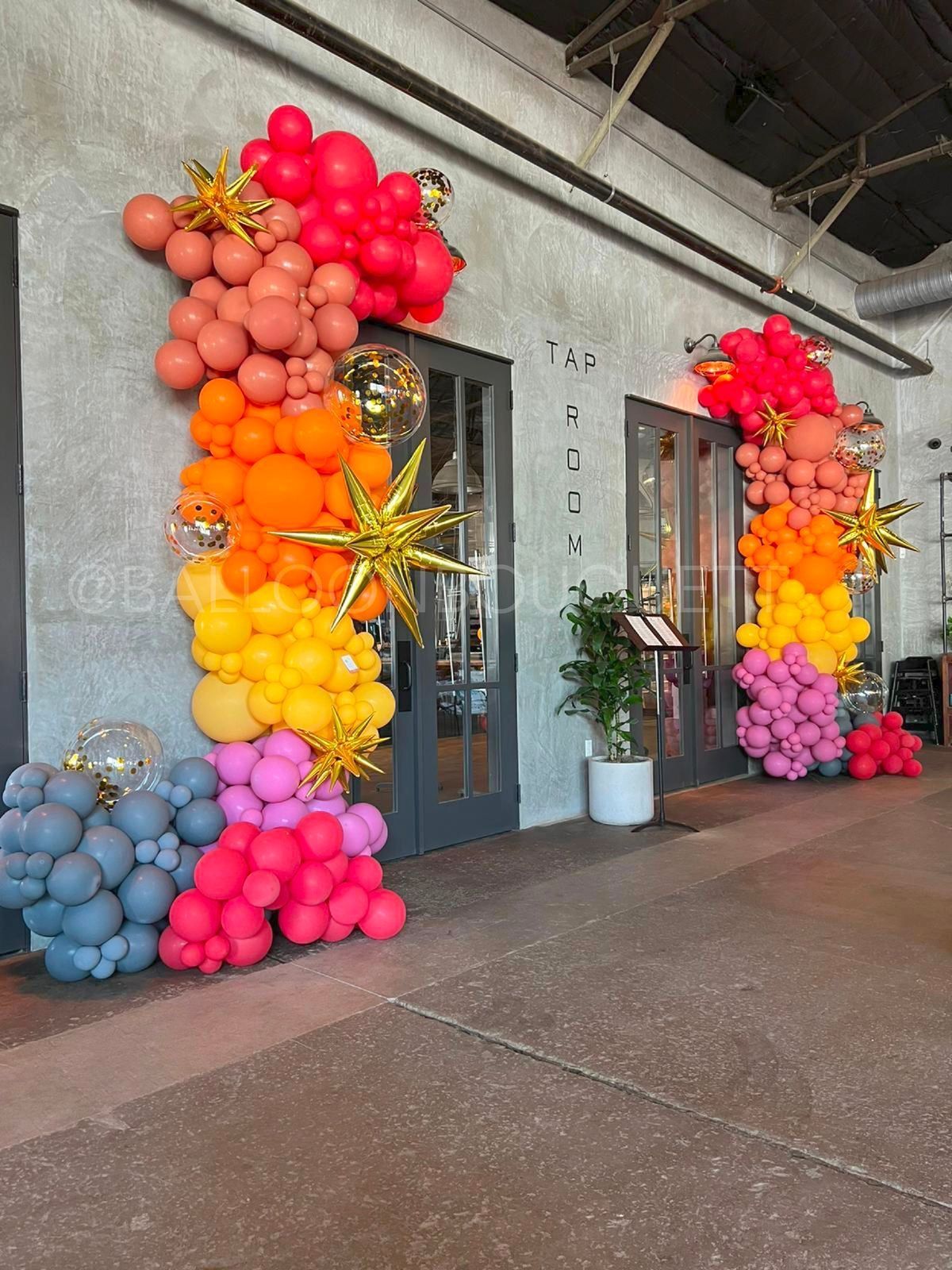 A bunch of balloons are hanging on a wall in front of a building.