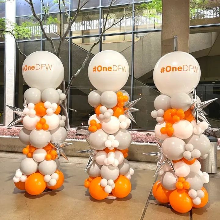 Three columns made of orange and white balloons with the words onedfw on them