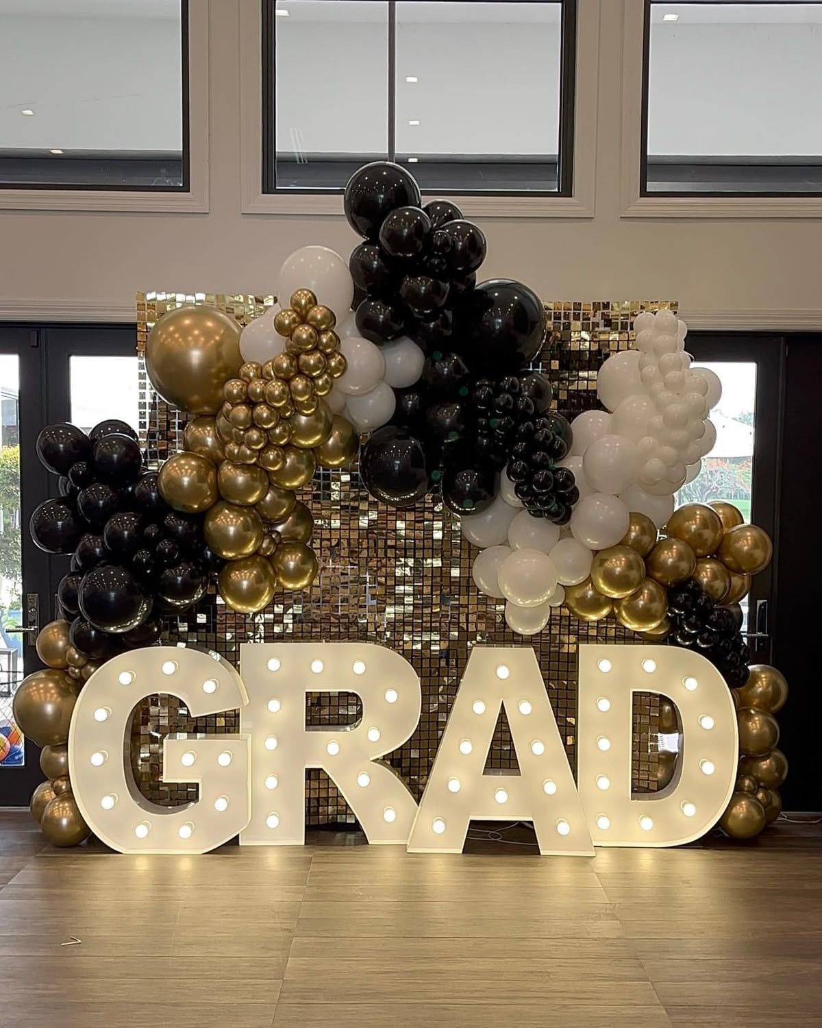 A large sign that says `` grad '' is surrounded by balloons in a room.