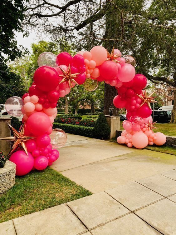 Pink balloon arch decorating a garden walkway for an outdoor celebration