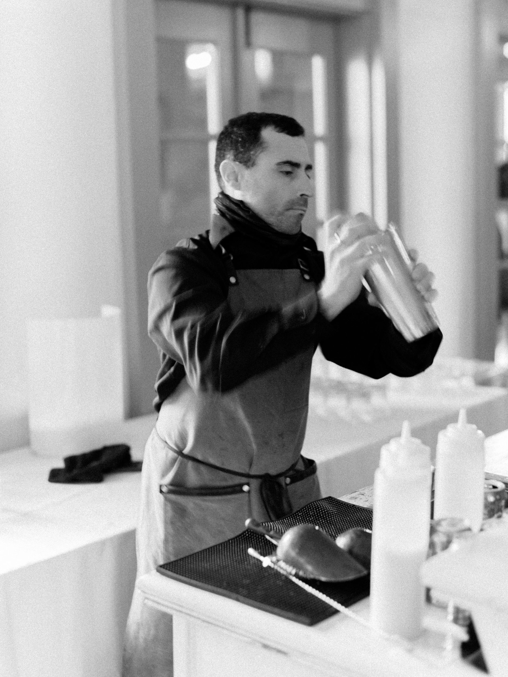 A man is shaking a drink in a black and white photo