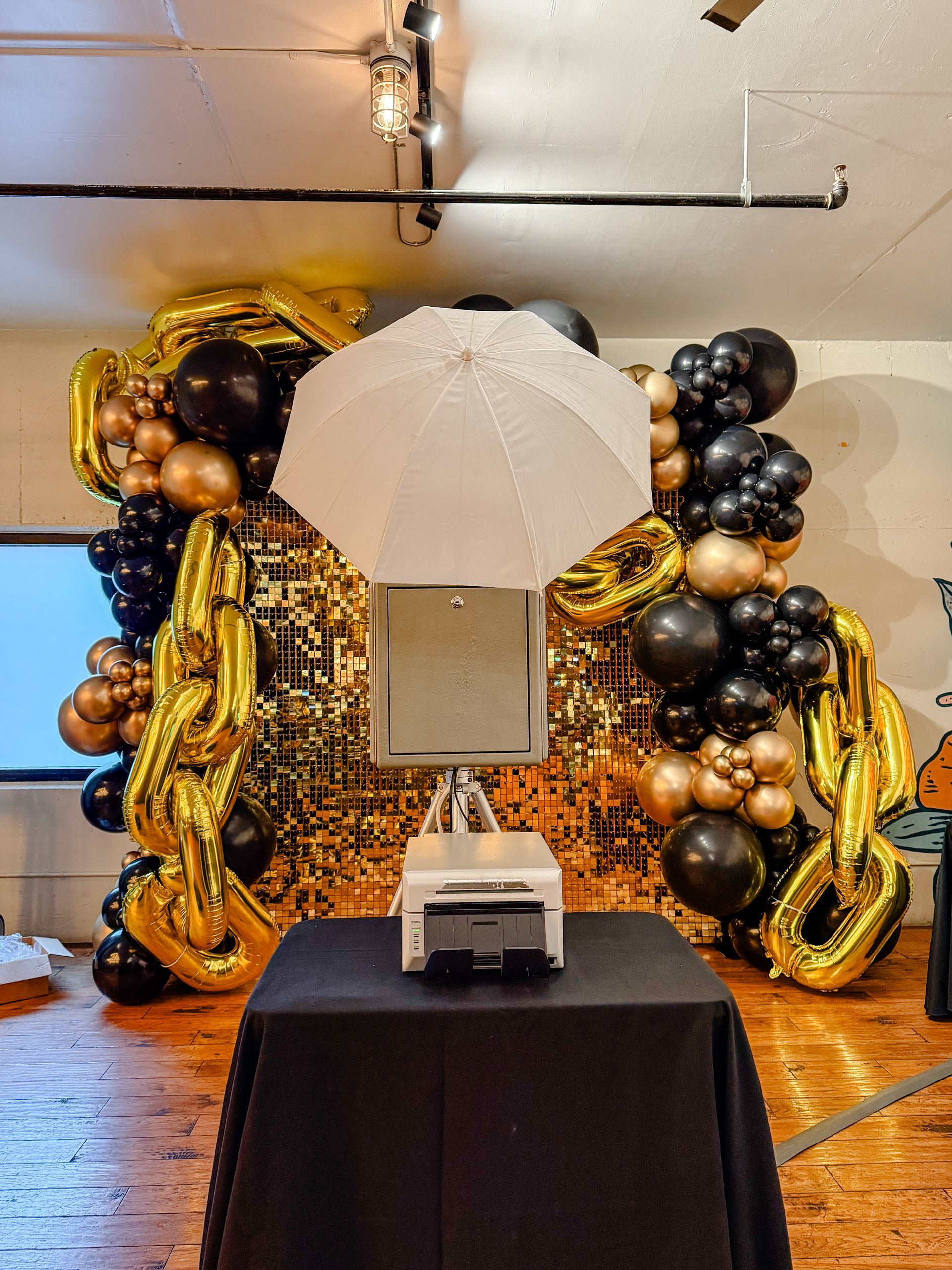 A photo booth is sitting on a table in front of a wall of balloons.
