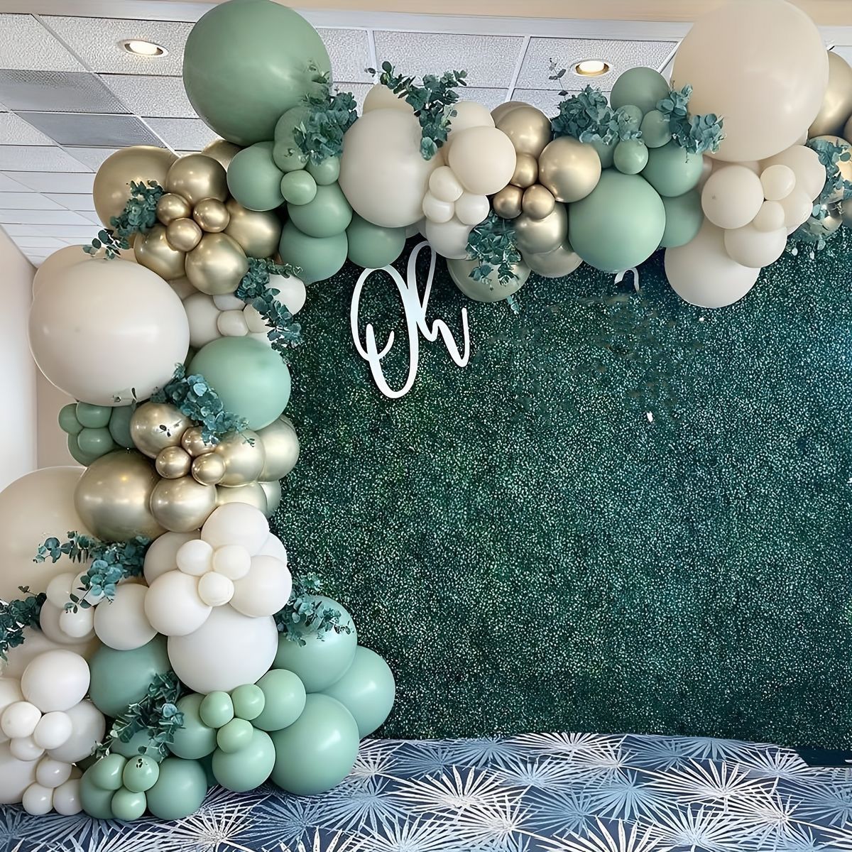 A green wall with balloons and flowers on it