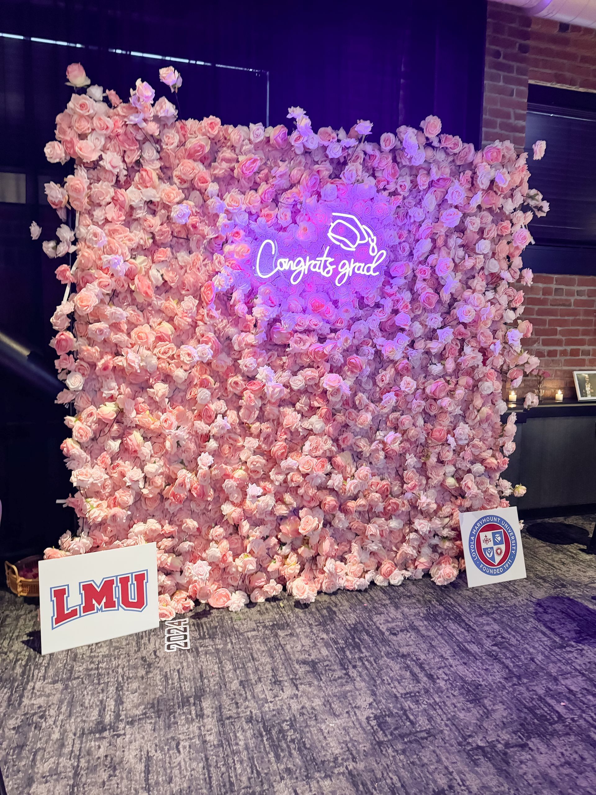 A wall of pink flowers with a neon sign that says `` congratulations ''.