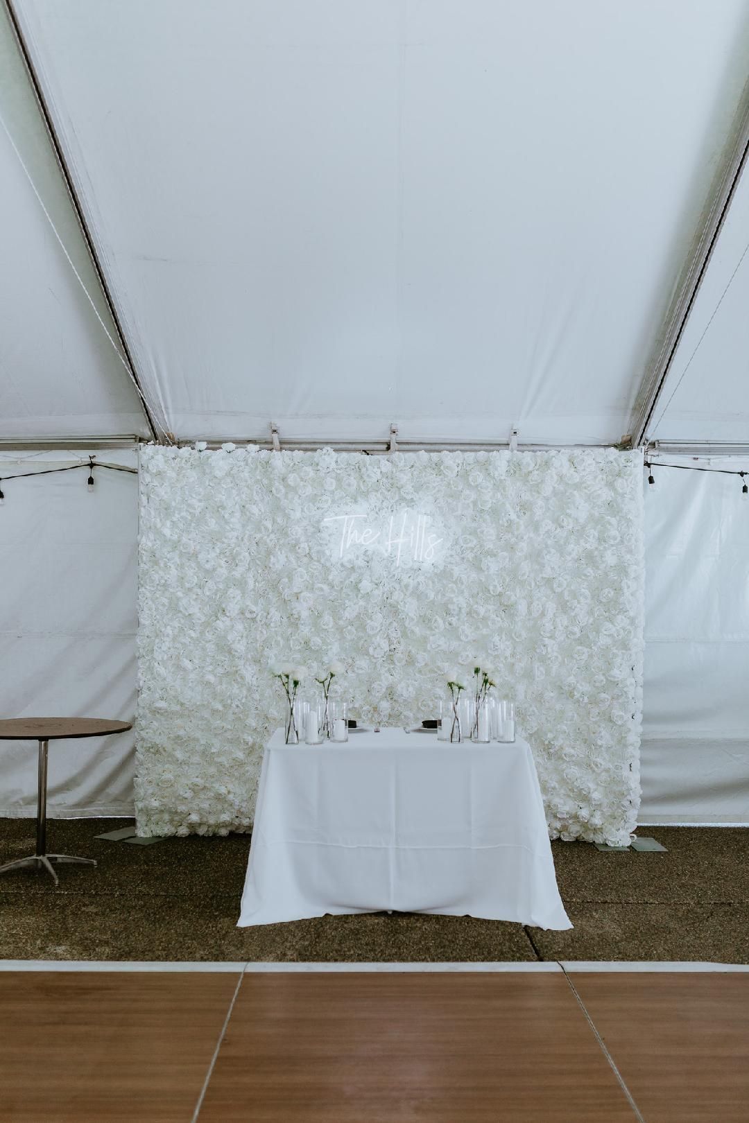 A wall of white flowers and balloons with a neon sign that says the thunders.