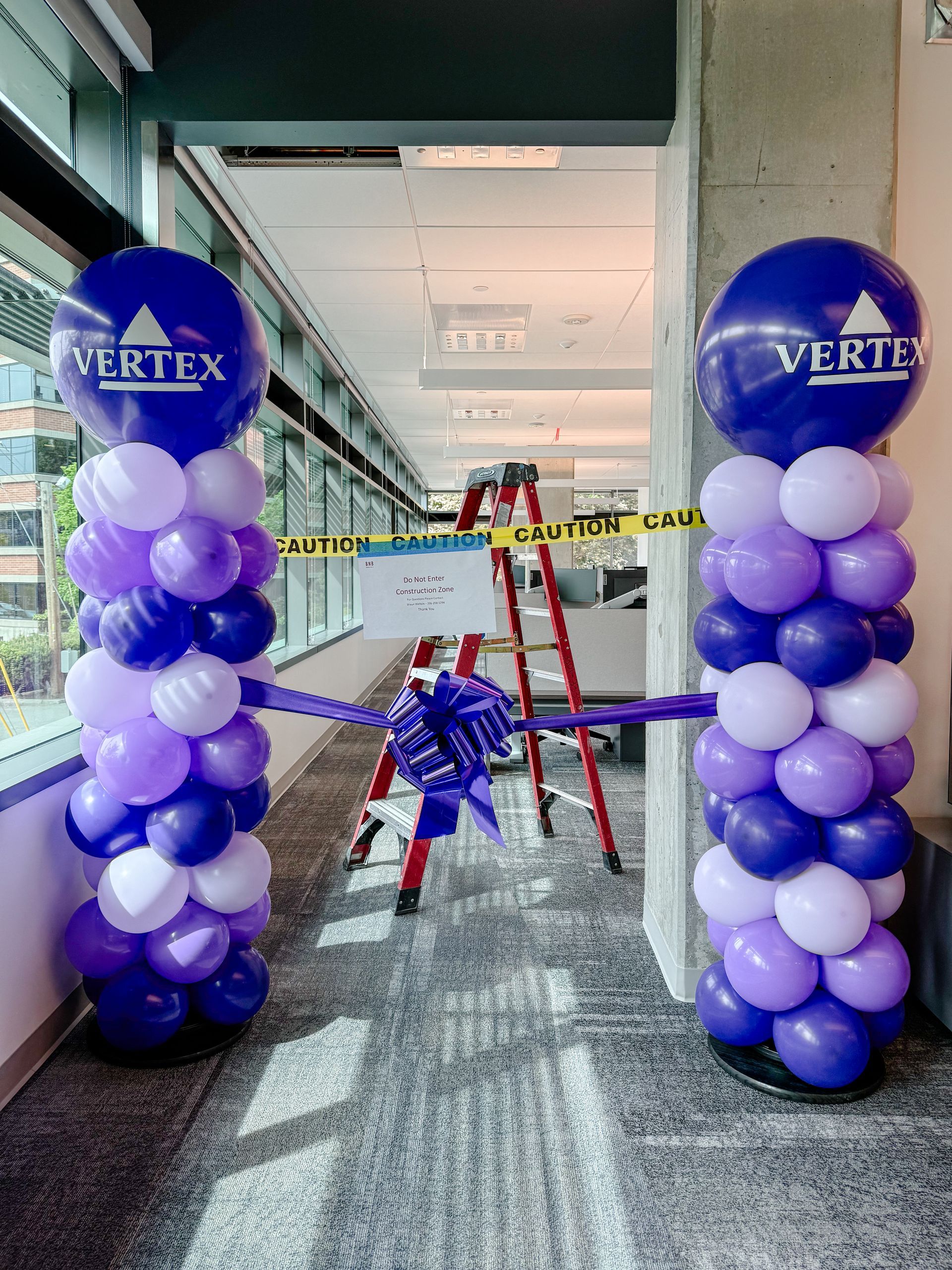 Balloon columns with a ribbon marking the opening of a Vertex office.