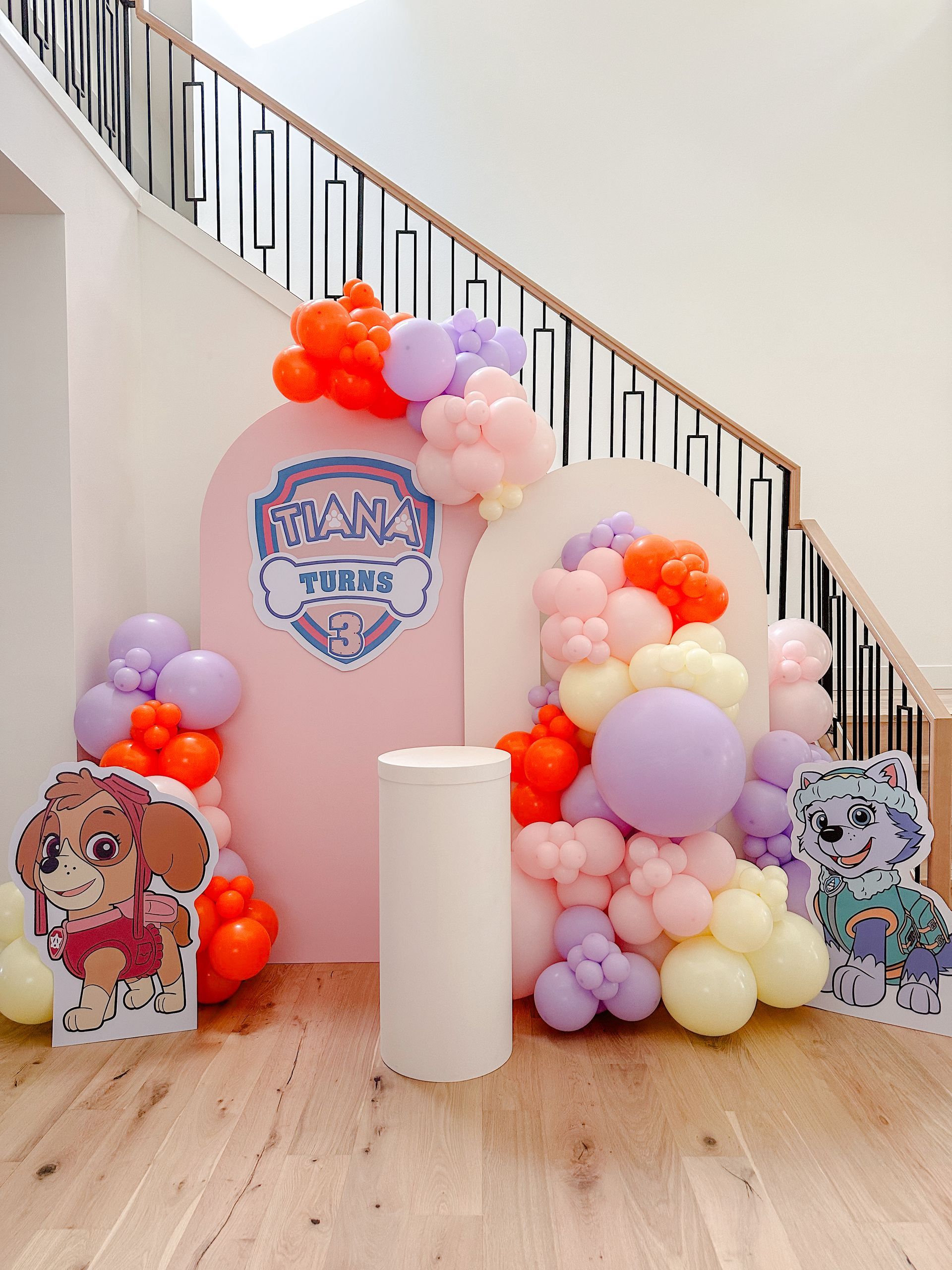 A room filled with balloons and a staircase in the background.