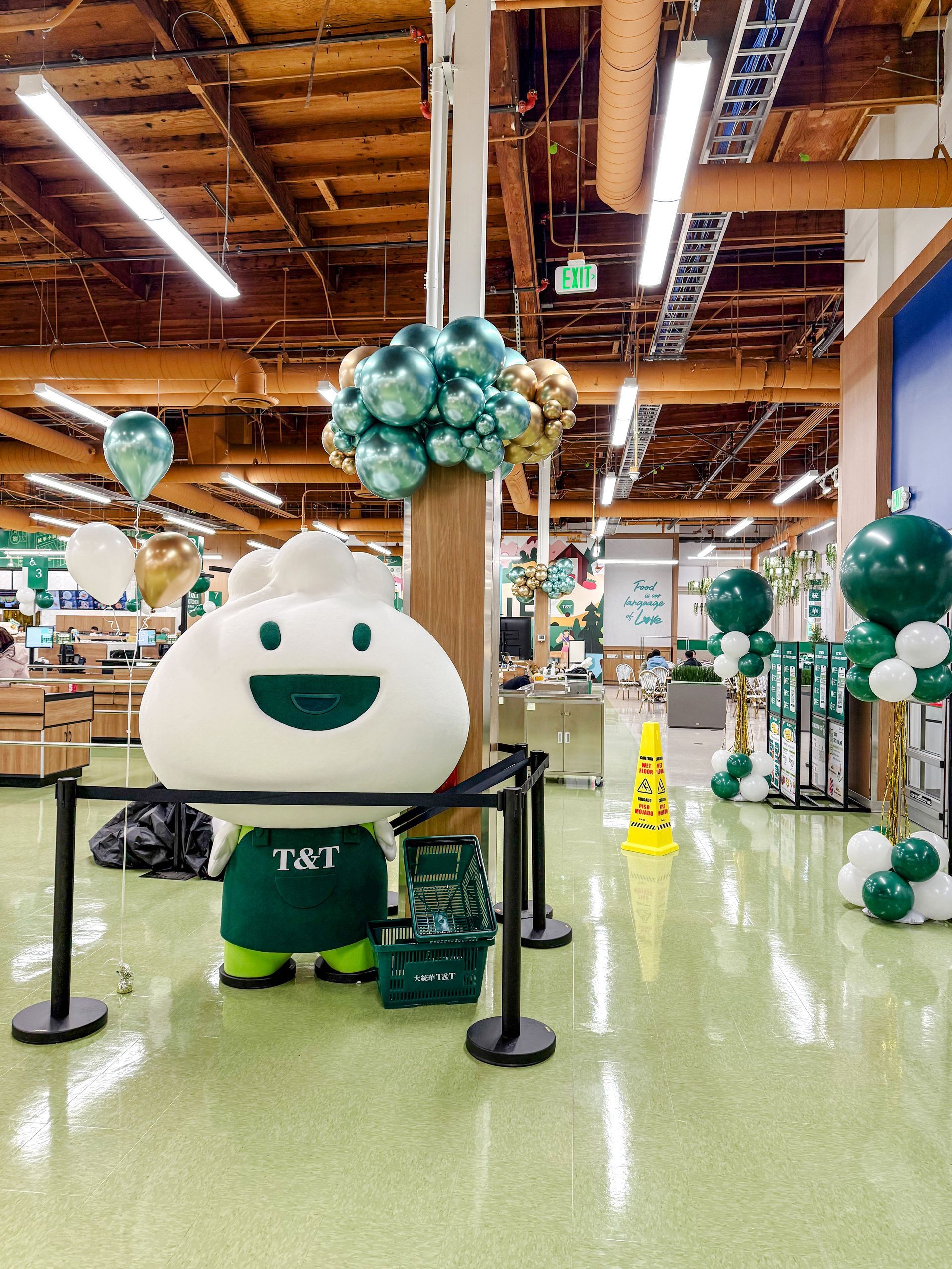 A mascot is standing in a store with balloons.