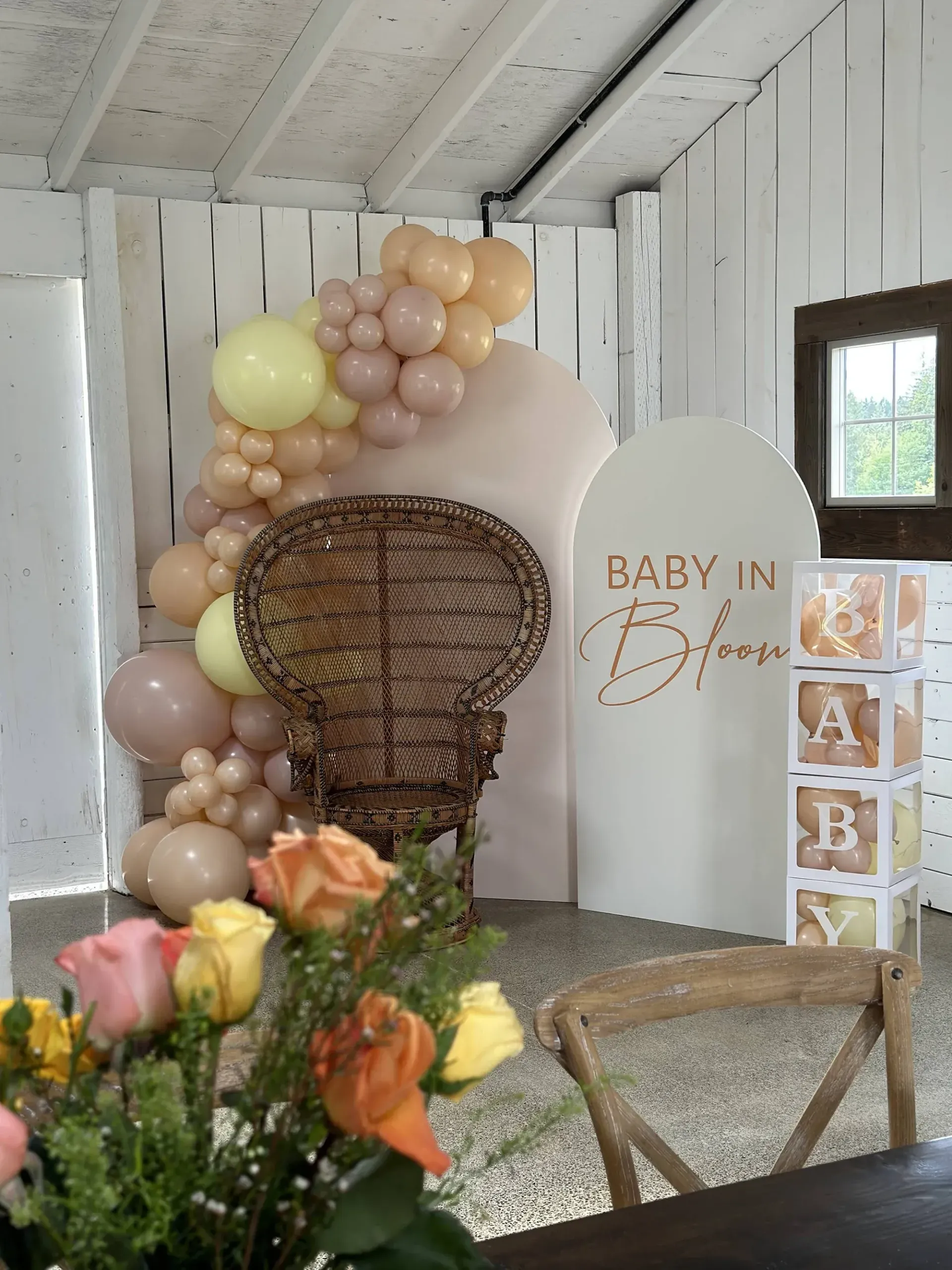 A room decorated with balloons and flowers for a baby shower.