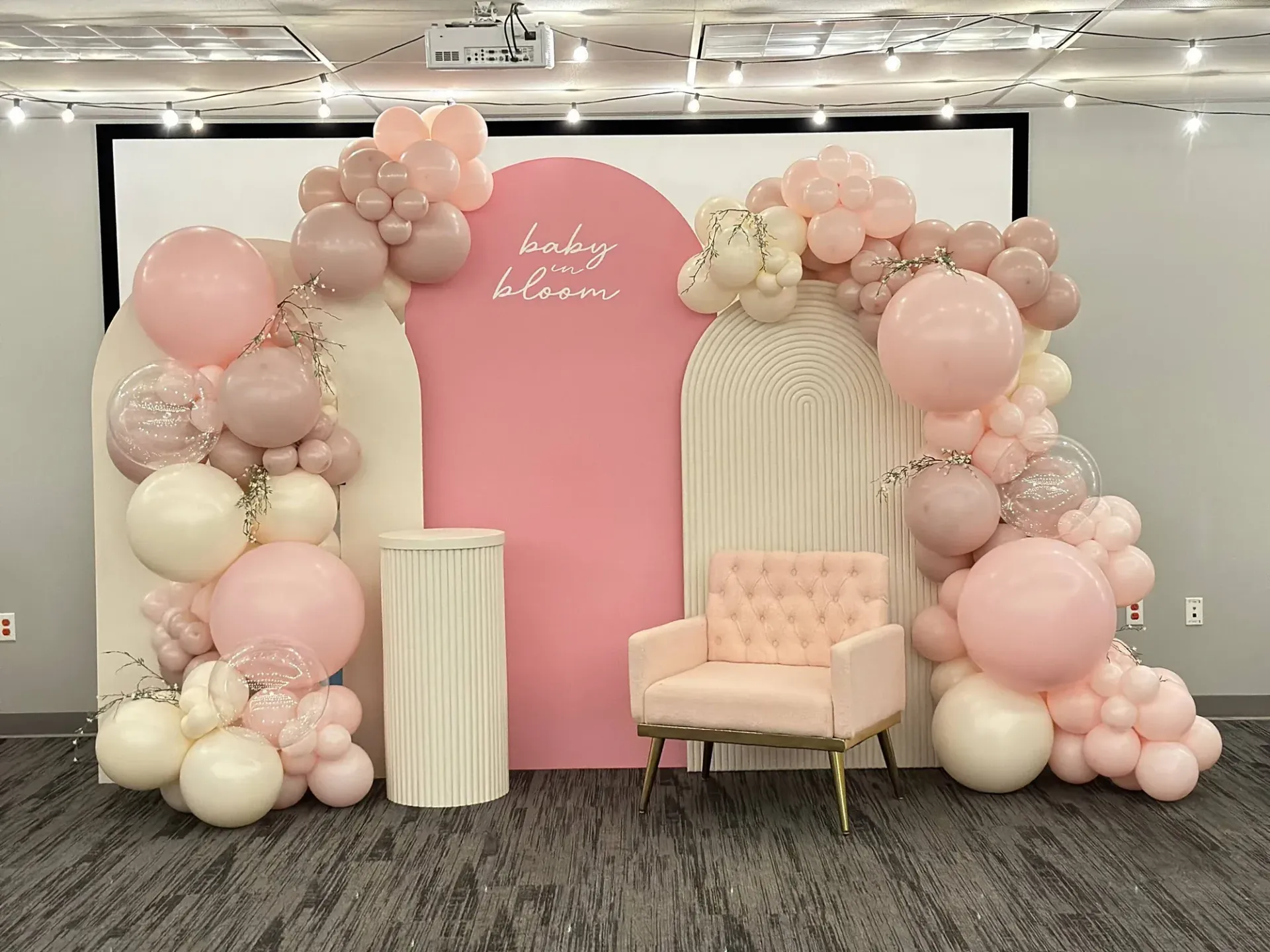 A room decorated with pink and white balloons and a chair.