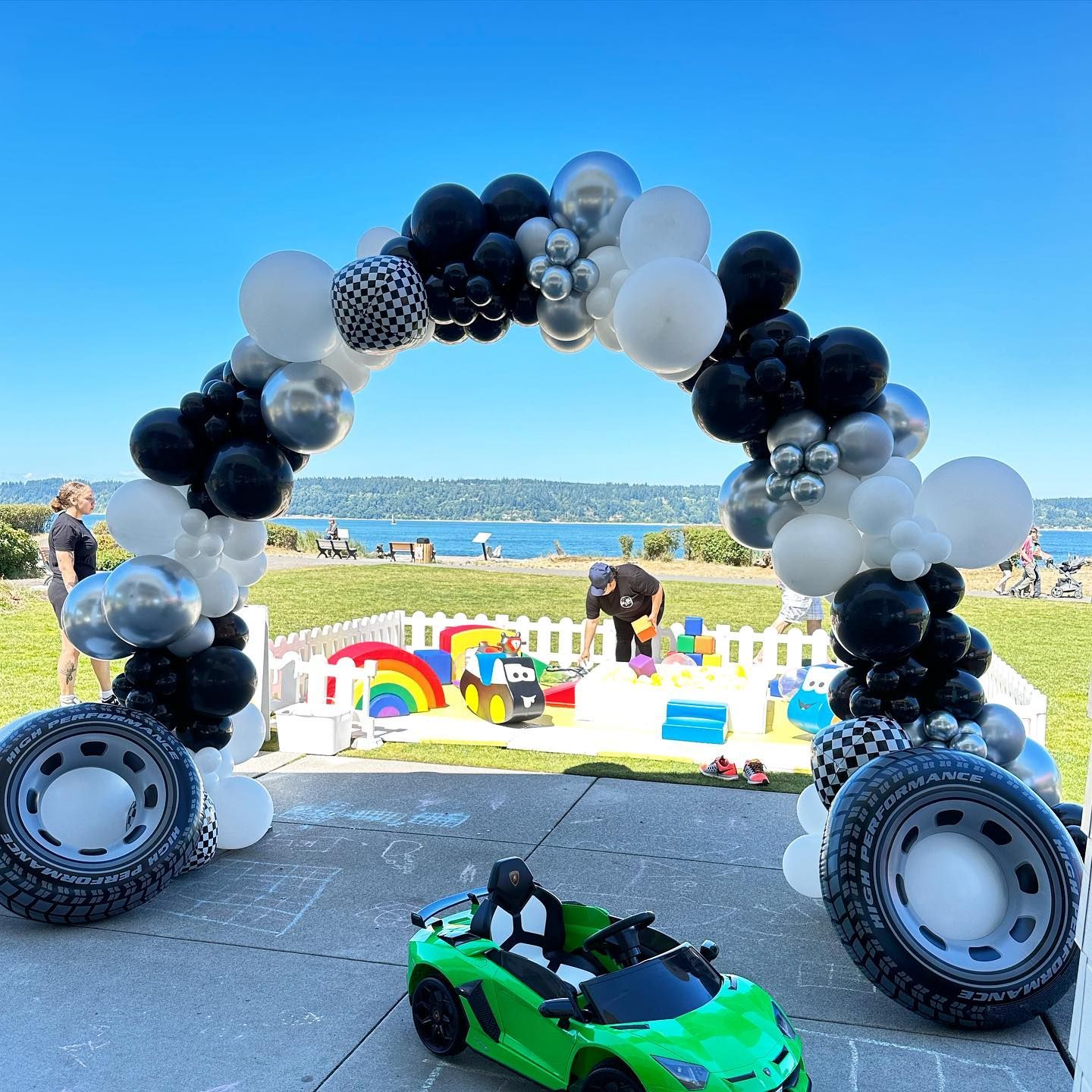 A green toy car is sitting under a balloon arch.