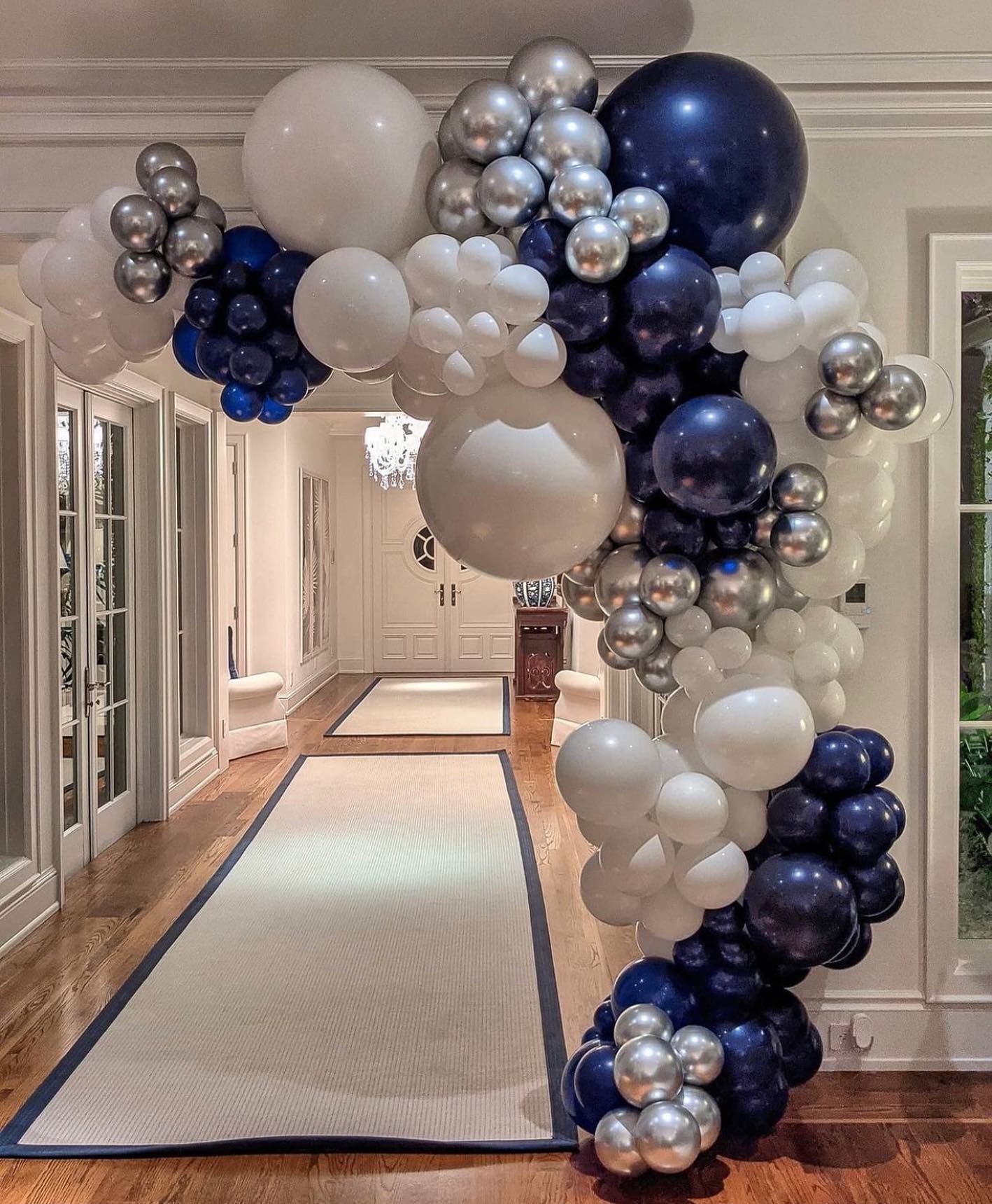 A hallway filled with blue , white , and silver balloons.