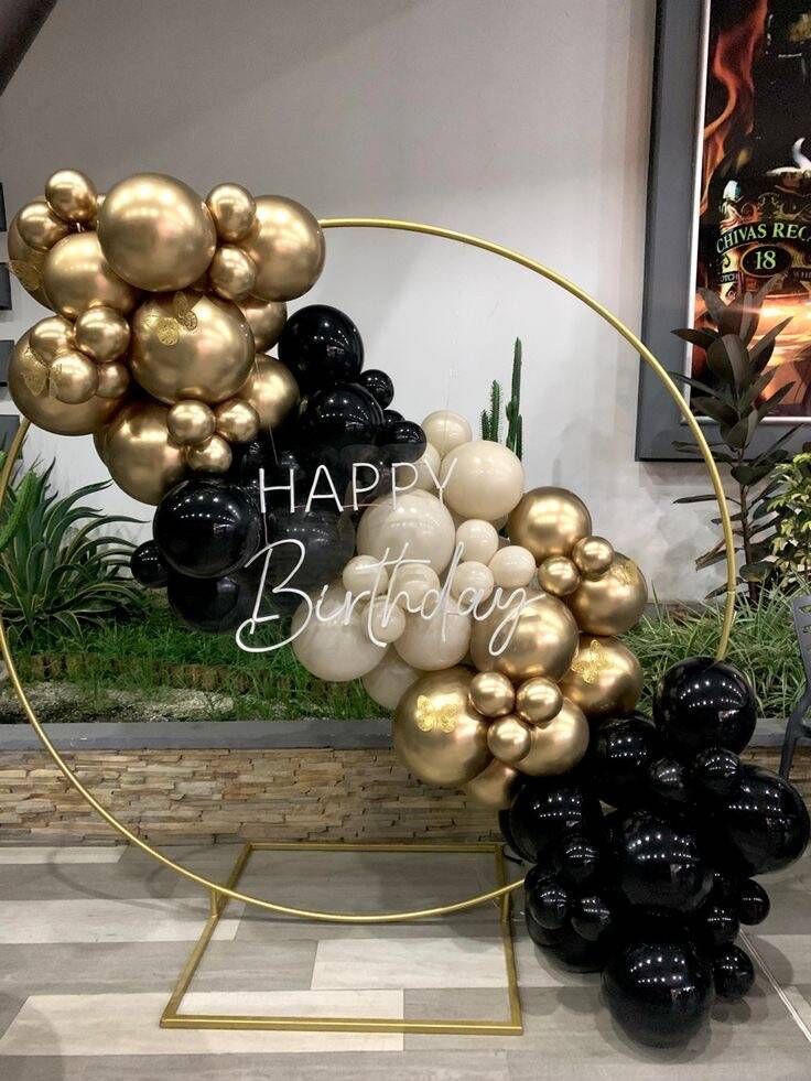 A circle filled with black and gold balloons for a birthday party.