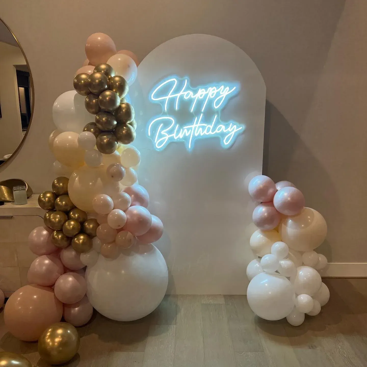 A neon sign that says `` happy birthday '' is surrounded by balloons.