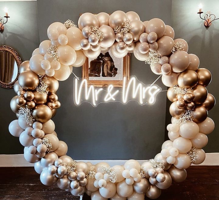 A neon sign that says mr and mrs is surrounded by balloons