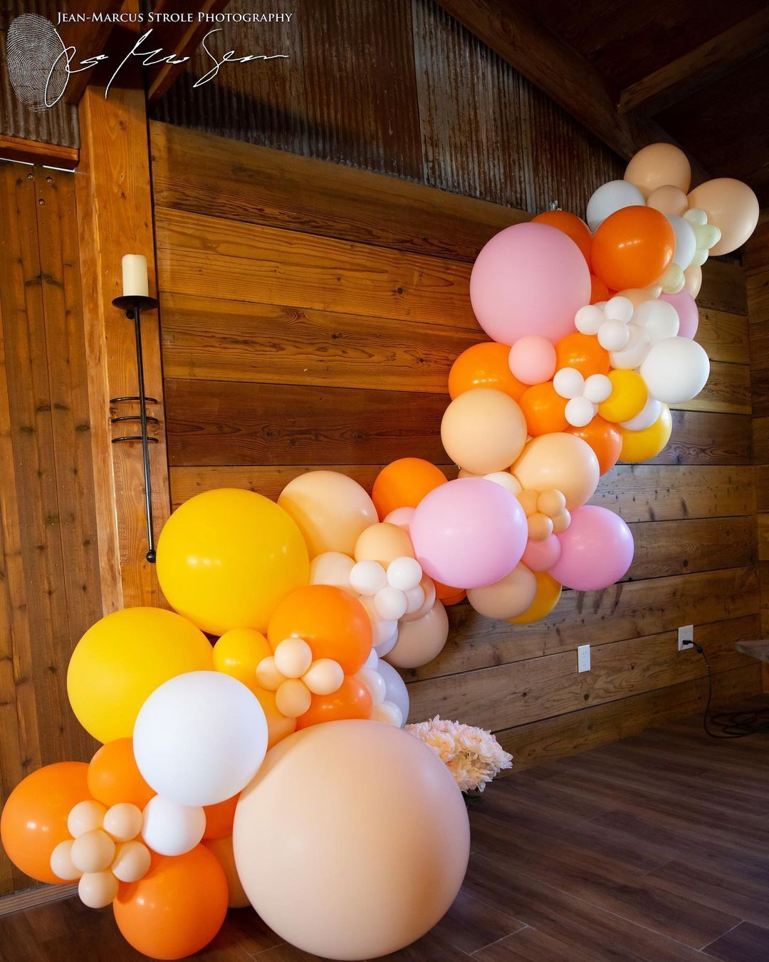 A bunch of balloons are hanging on a wooden wall