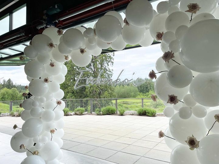 A bunch of white balloons are hanging from the ceiling in a room.