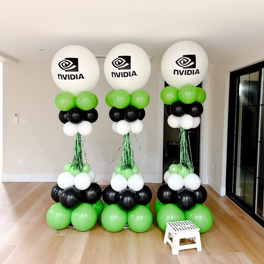 Three NVIDIA logo balloon columns in a room. Each features green, black, and white balloons. A small white stool is present.