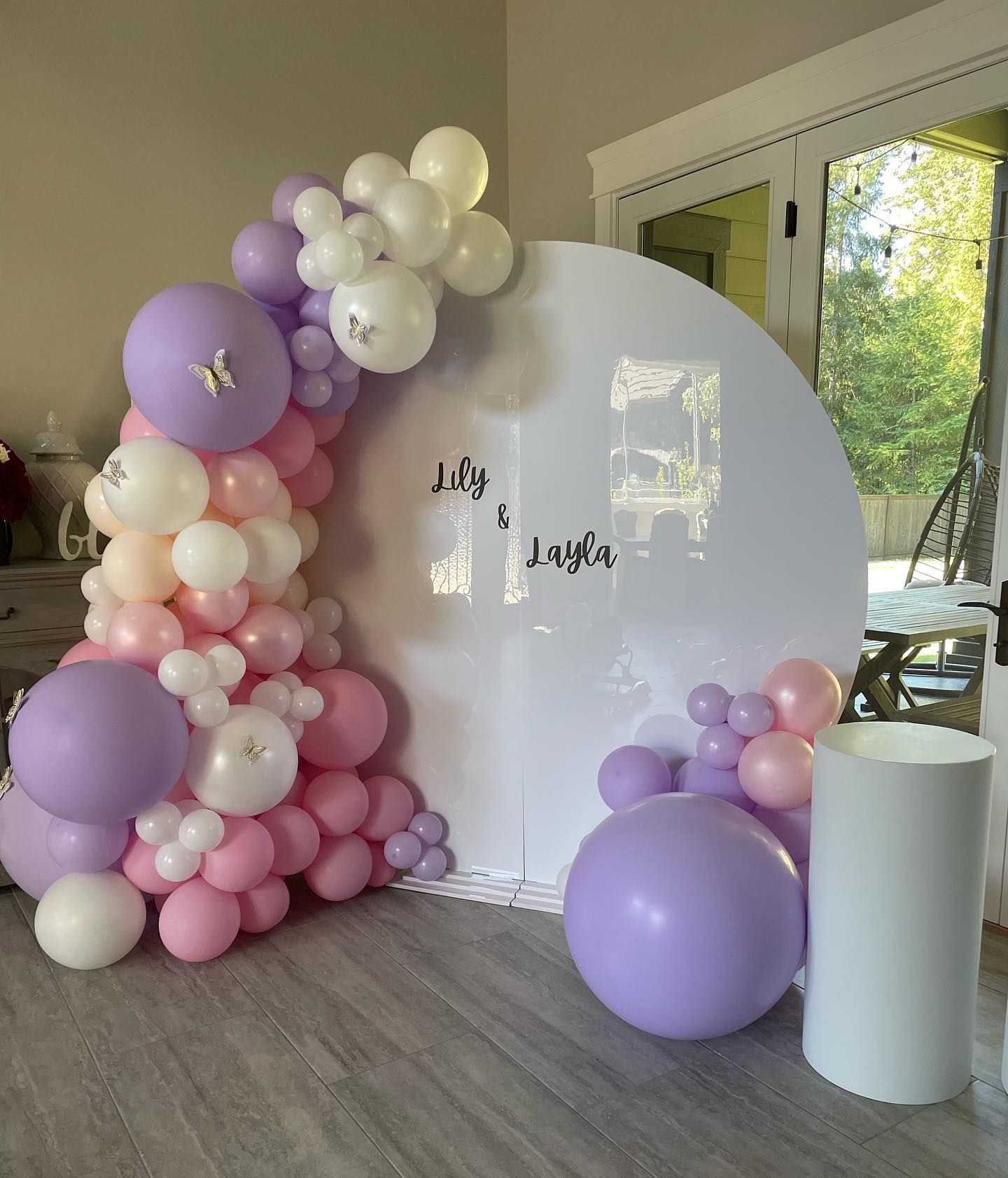 A room decorated with pink and purple balloons and a white pillar.