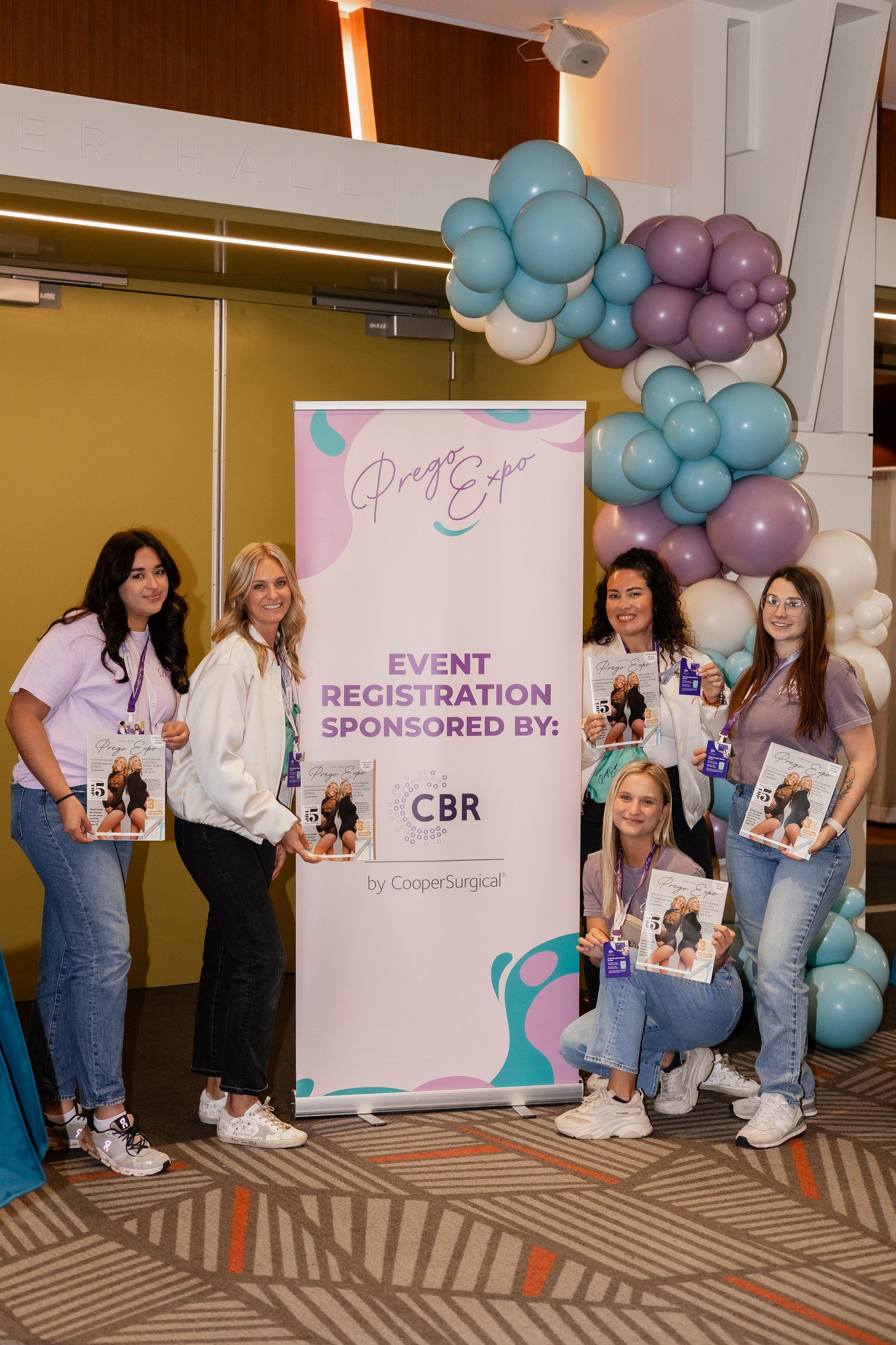 A group of women are standing in front of a sign that says event registration sponsored by.