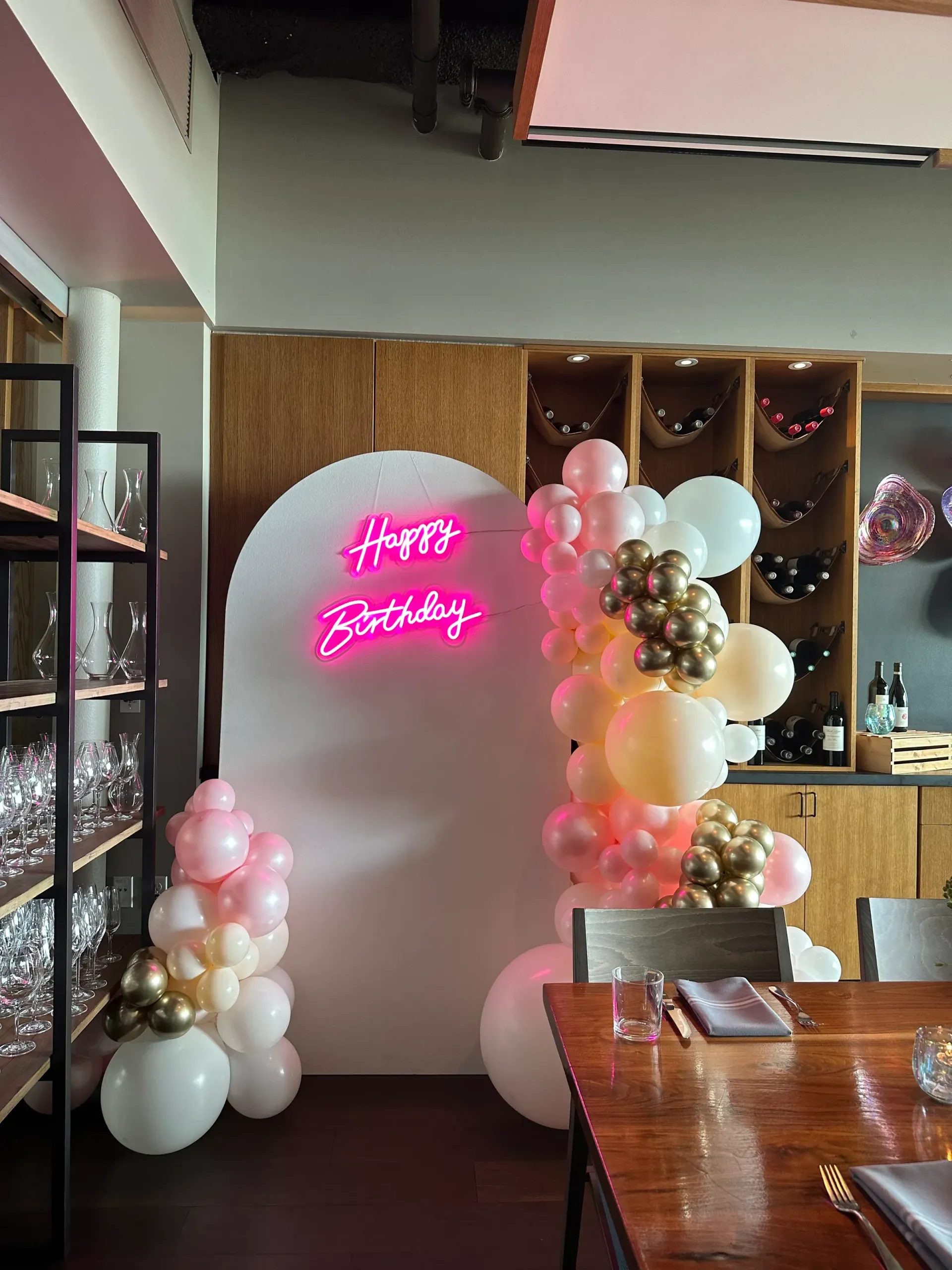 A room filled with balloons and a neon sign that says `` happy birthday ''.