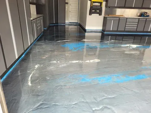 Explore a wide-angle view of a garage project, featuring a seamless silver metallic base coat elevated with striking ocean blue pearlescent waves.    Custom Silver & Ocean Blue Metallic Floor by Global Garage Flooring & Design Houston