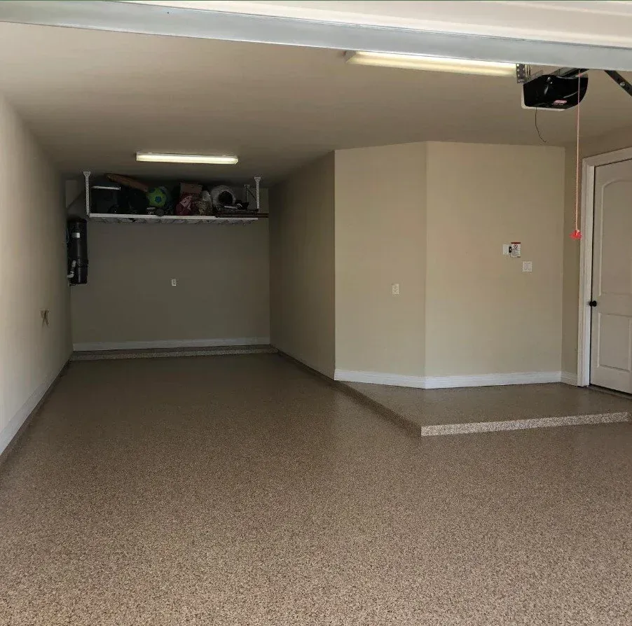Empty beige-carpeted garage with a raised platform and shelves in the back.