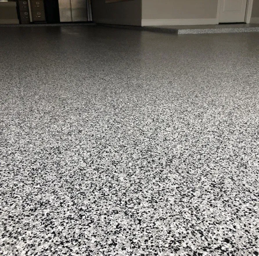 Speckled gray epoxy floor in a room with white walls and cabinets along the back.