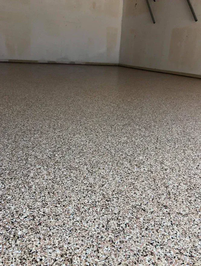 Empty room with speckled gray floor and plain beige walls