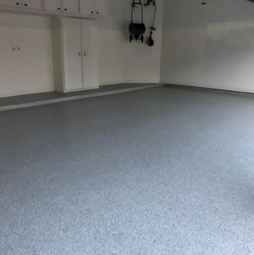 Empty carpeted garage interior with white walls and closed double doors