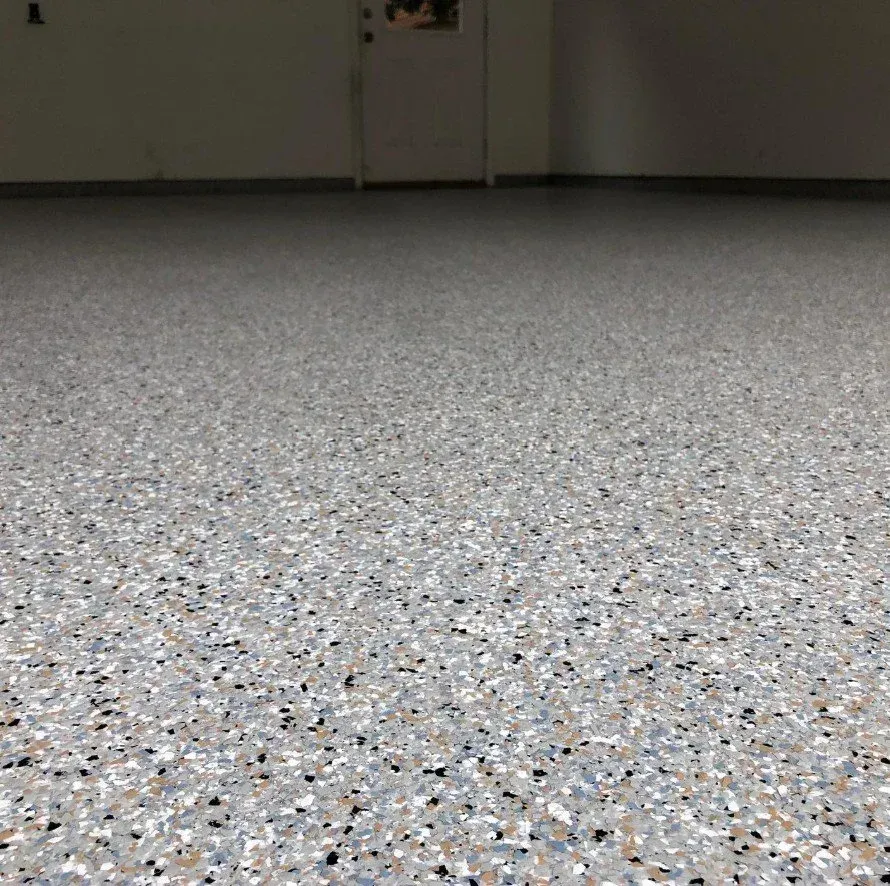 Empty speckled floor in a dim room, with a closed door in the background.